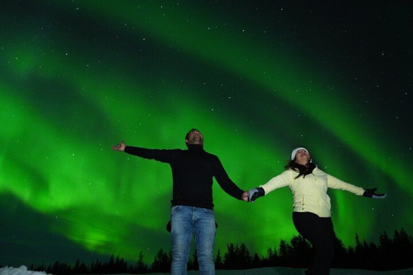Twee mensen die hand in hand staan onder een groene poollichtverschijning. 2