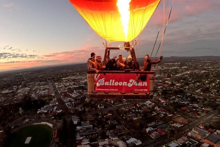 Een luchtballon met passagiers boven een stadsgezicht tijdens de zonsondergang. 1