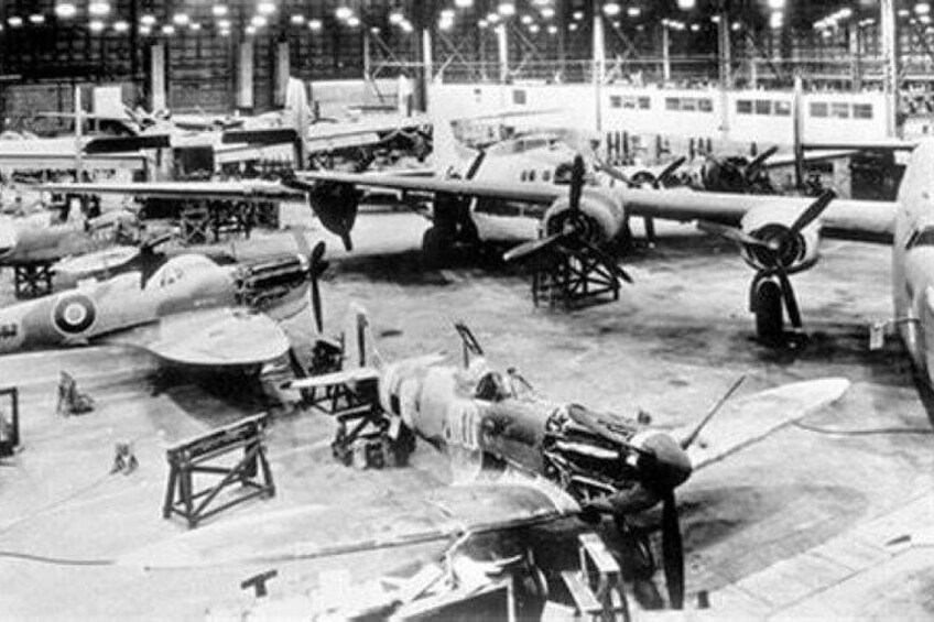A large hangar with multiple aircraft, including fighter planes and bombers, in various stages of assembly or maintenance. 5