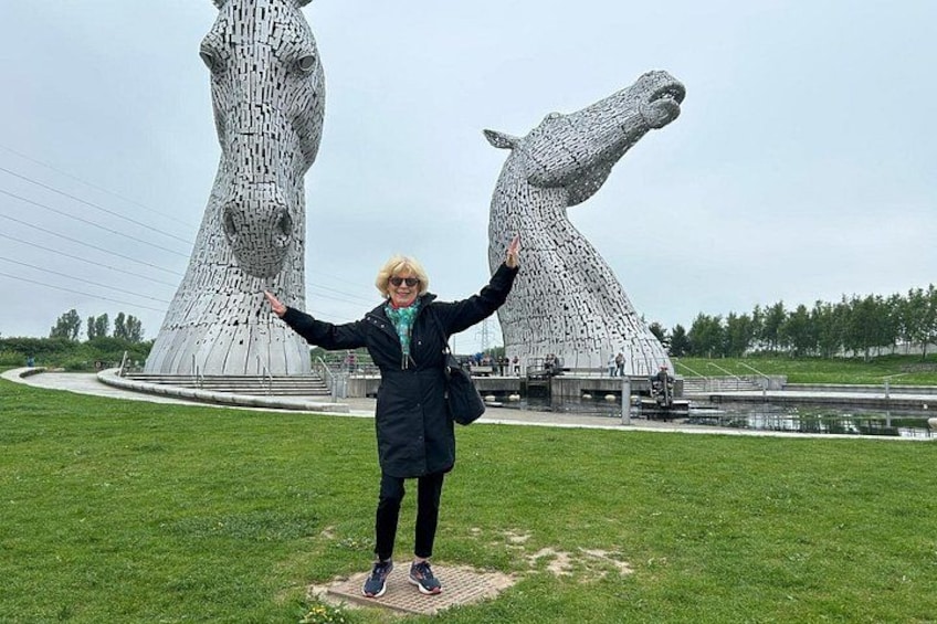 Une personne se tient devant les Kelpies, deux grandes sculptures blanches en forme de chevaux. 5