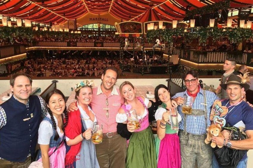 A group of people in traditional attire at a festival, with a stage and audience in the background. 1