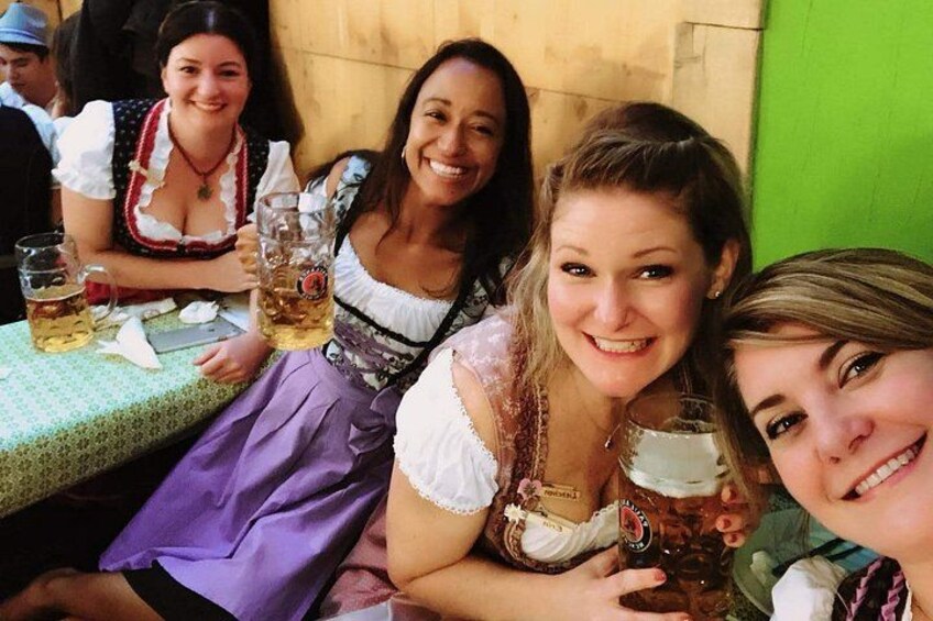 People in traditional Bavarian attire at a table with beer mugs. 5