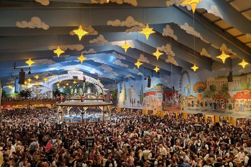 A crowded indoor event with a stage, star decorations, and a large audience. 4