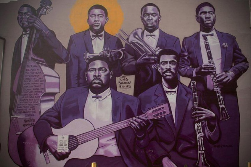 Un mural que muestra a cinco hombres con traje sosteniendo instrumentos musicales. 1