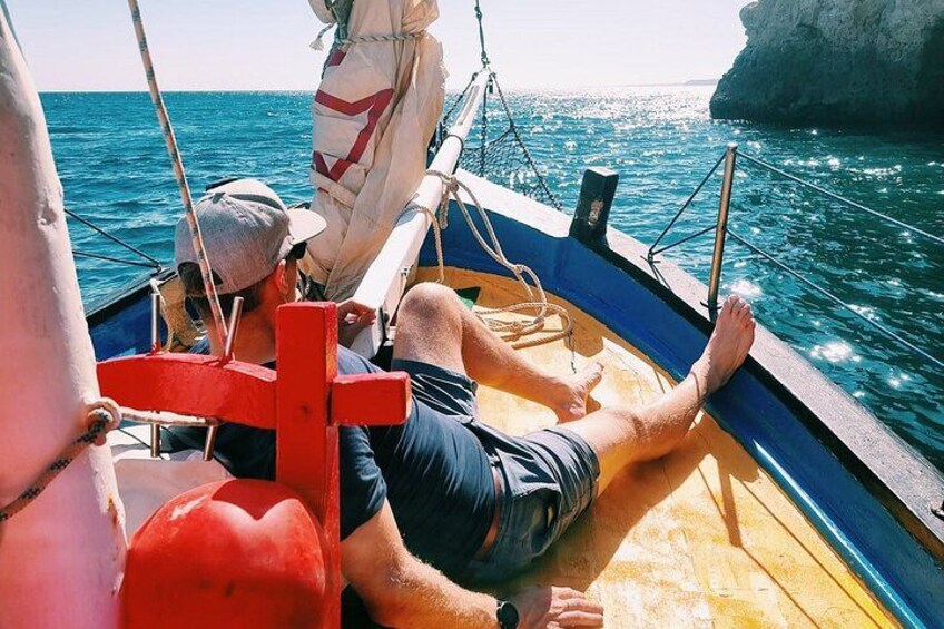 Una persona en un velero con un litoral rocoso al fondo. 4