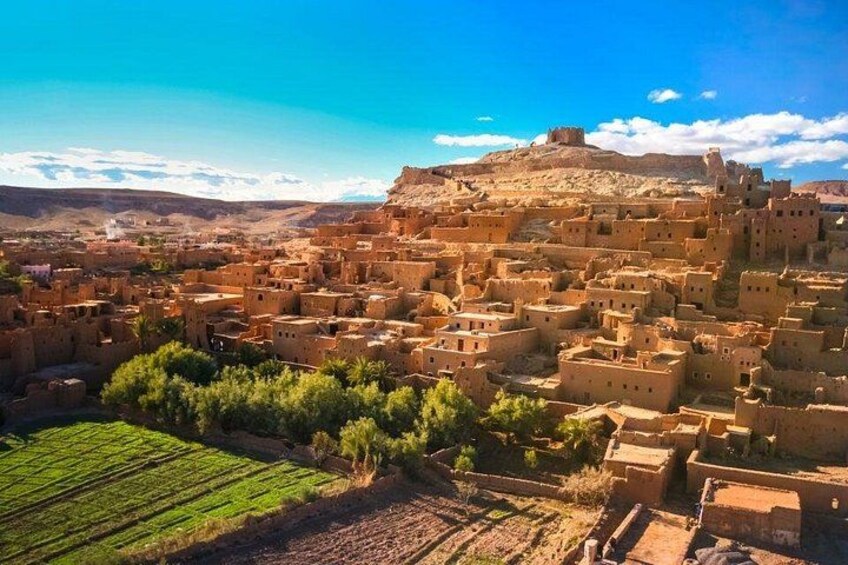 A desert town with adobe buildings, terraced fields, and a hilltop fortress. 4