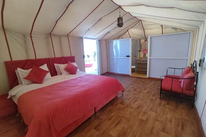 A tent with a bed, a chair, and a small table. 2