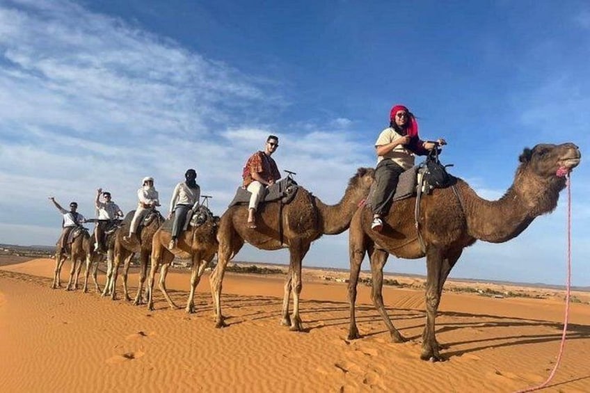 A group of people riding camels across a desert landscape. 4
