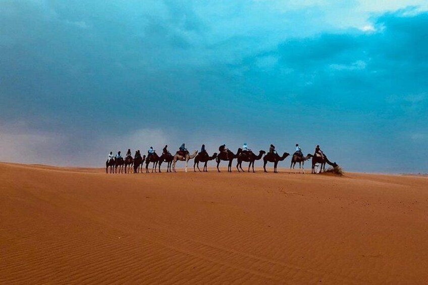 A group of people riding camels across a desert landscape. 3
