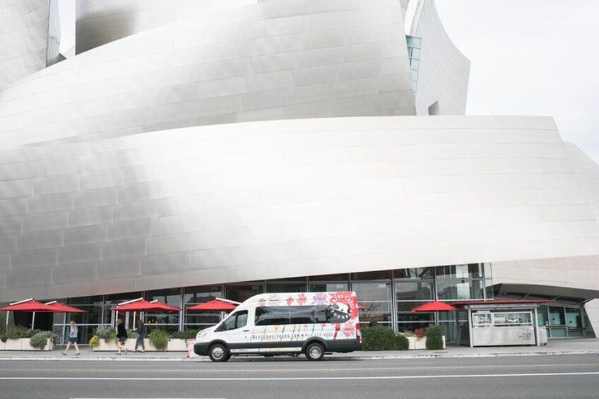 Een modern gebouw met een gebogen gevel en rode parasols. 4