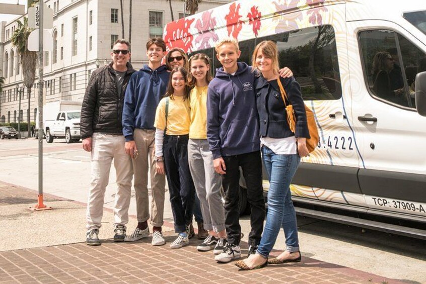 Een groep mensen staat voor een witte bus met rode Chinese karakters op de zijkant. 1
