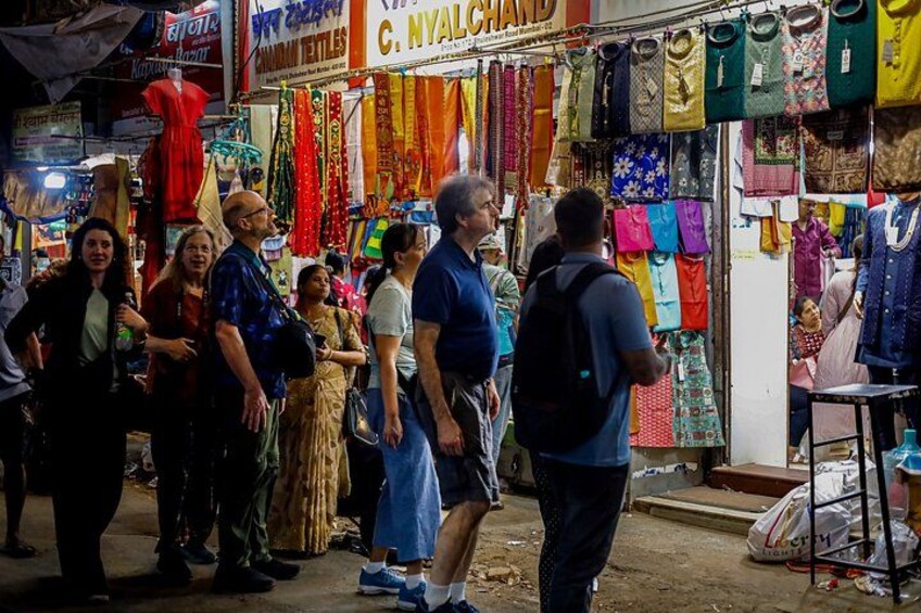 A busy market with people shopping and a store named 'C. Nyalchand' in the background. 4