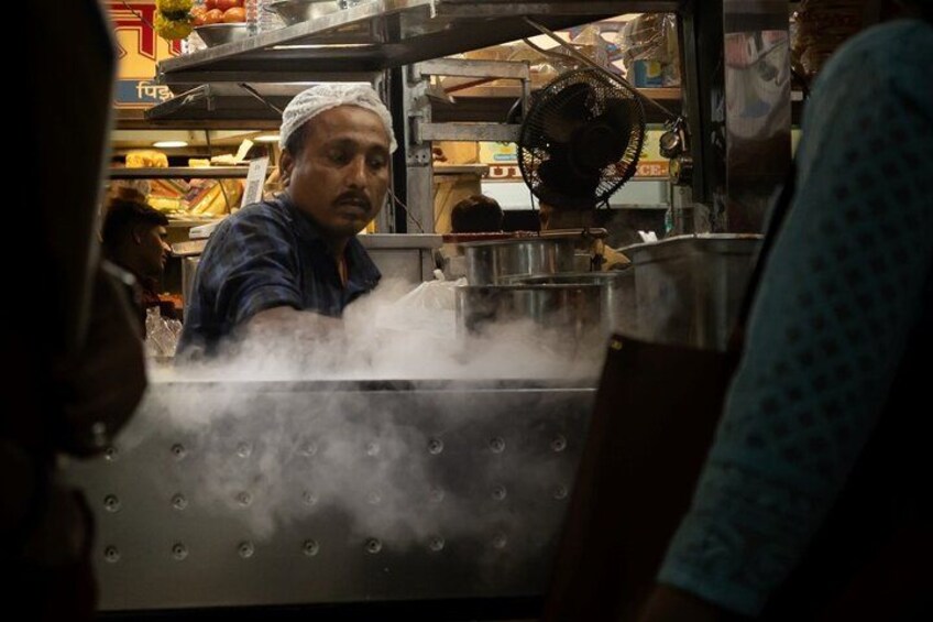 A person cooking in a kitchen with steam rising from a pot. 4