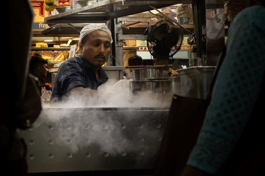 A person cooking in a kitchen with steam rising from a pot. 2