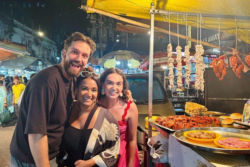 A street food stall at night with various meats and a yellow canopy. 1