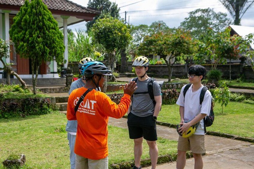Three people standing outdoors, one wearing an orange shirt with a helmet, another in a grey shirt, and the third in a white shirt. 2