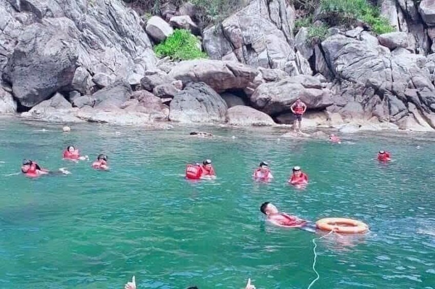Des personnes flottent dans une étendue d’eau, avec des rochers en arrière-plan. 5