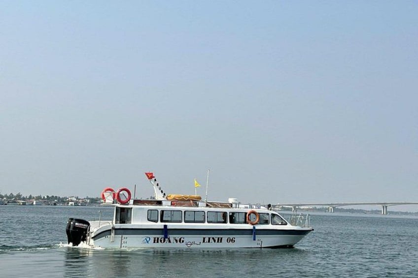 A boat named 'HOANG LINH 06' on water with a bridge in the background. 2