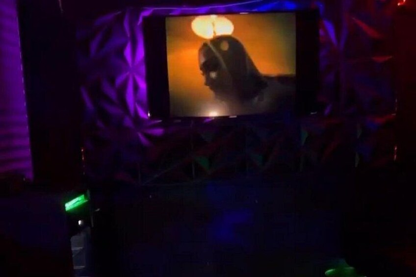 A dimly lit room with a television displaying a person. 3