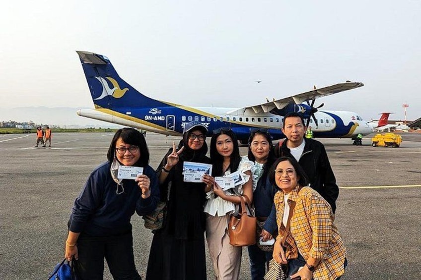 A group of people posing in front of an airplane on a tarmac. 3