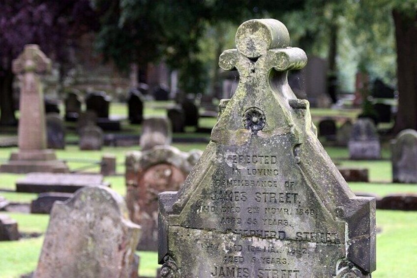 A gravestone with inscriptions, surrounded by other gravestones in a cemetery. 2