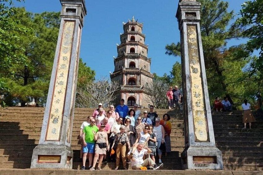 Een groep mensen bij een historisch complex met een pagode-achtige structuur op de achtergrond. 5