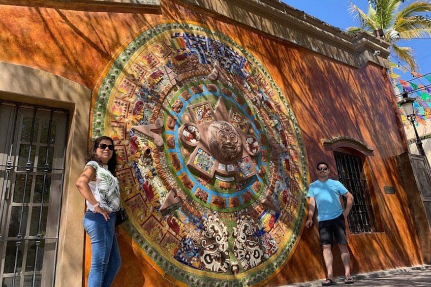 A mural with a circular design and a person standing in front of it. 1