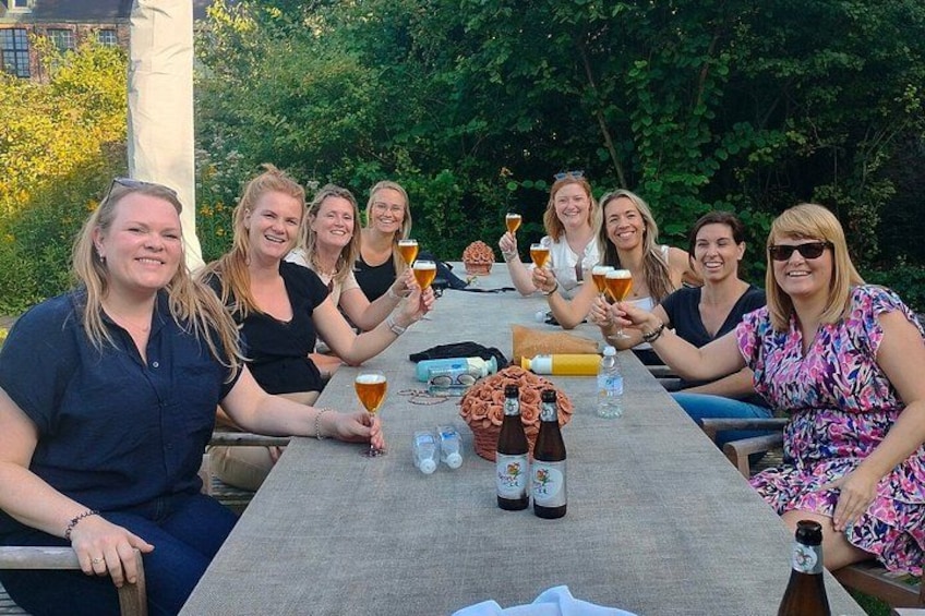 Eine Gruppe von Personen sitzt draußen an einem Tisch und hält Biergläser. 4