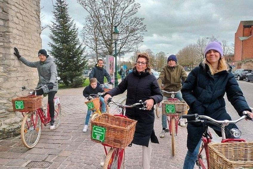 Eine Gruppe von Menschen fährt mit Fahrrädern auf einem asphaltierten Weg. Die Fahrräder haben Körbe. 2