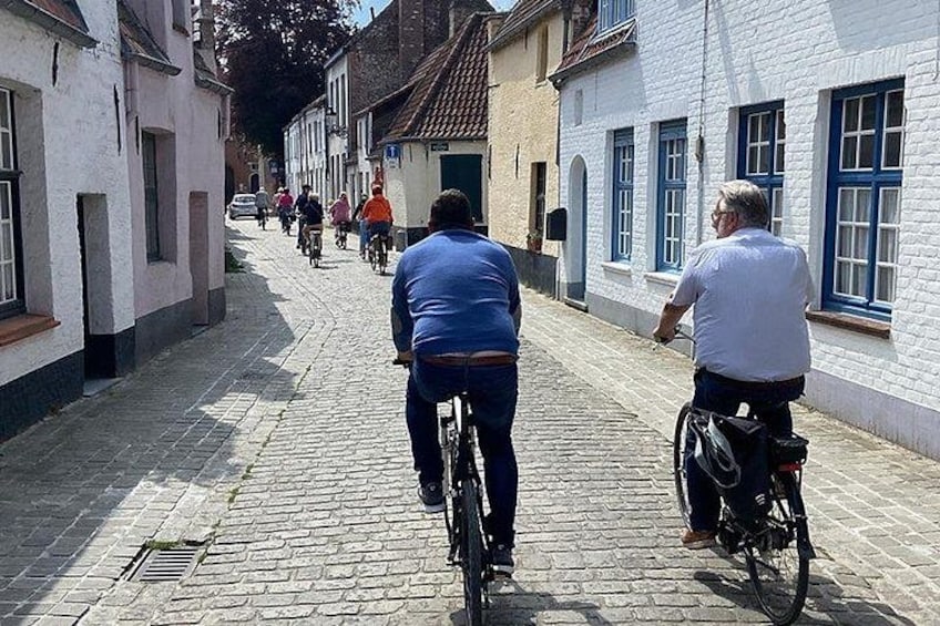 Eine Kopfsteinpflasterstraße mit Radfahrern und Fußgängern. 3