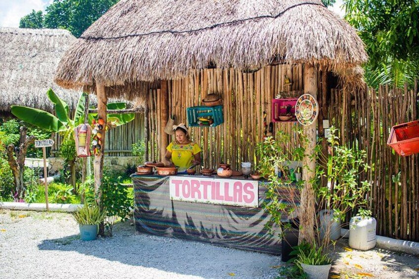A food stall with a sign reading 'TORTILLAS' in front of a thatched-roof hut. 3