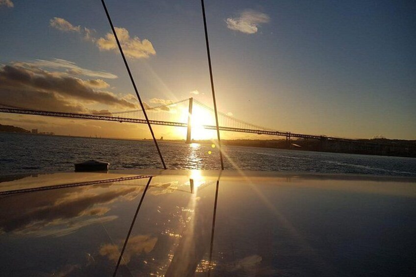 Ein Sonnenuntergang über einer Brücke, wobei sich die Sonne im Wasser spiegelt. 2
