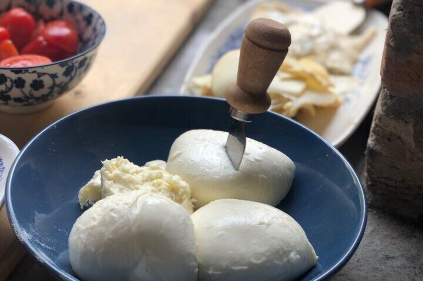 Een blauwe schaal met drie witte kaasbolletjes en een houten kaasschaaf. 1