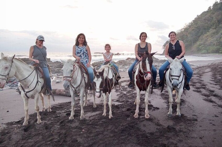 Un grupo de personas cabalgando en una playa, con el océano al fondo. 3
