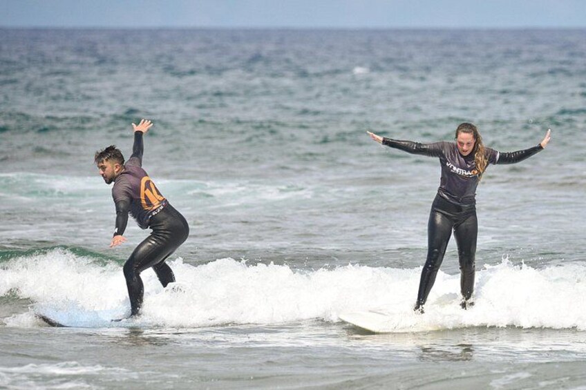 Twee mensen surfen op een golf in de oceaan. 3