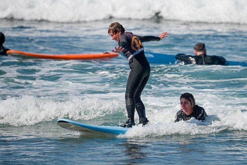 A person surfing on a wave, another person in the water, and a surfer on a blue board. 4