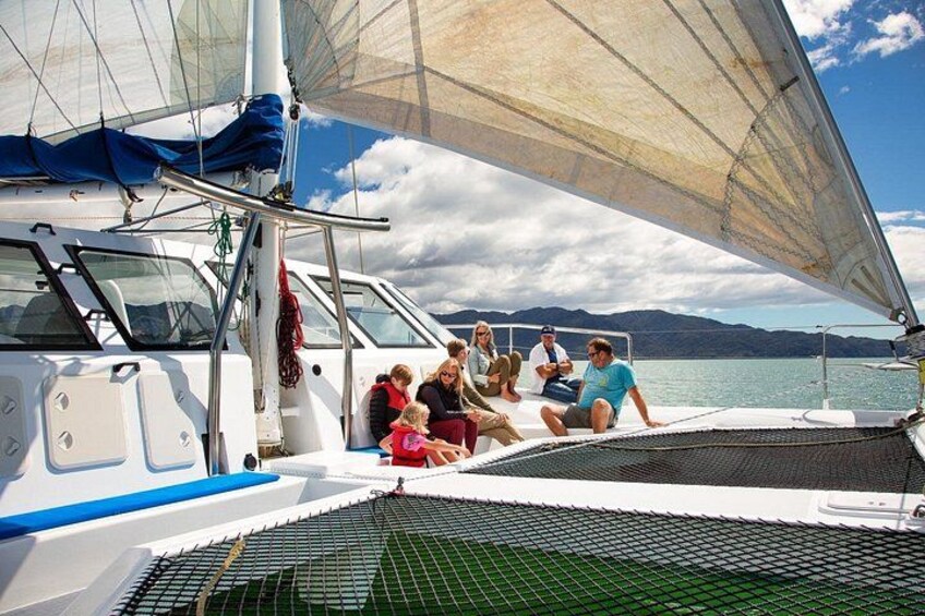 A sailboat with people on deck, a clear sky, and a calm sea. 4
