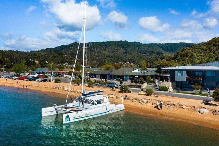 A white sailboat docked at a beach with a mountainous backdrop. 5