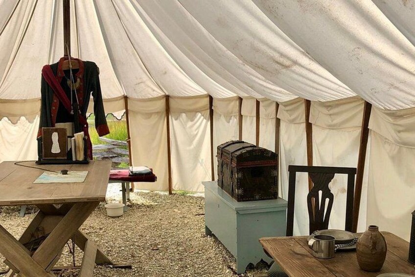 A tent with a table, a chair, a mannequin, and a display case. 3