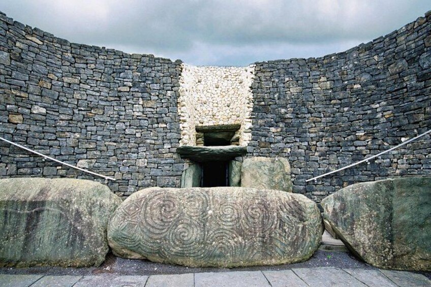 A stone structure with a central niche and large boulders in front. 2