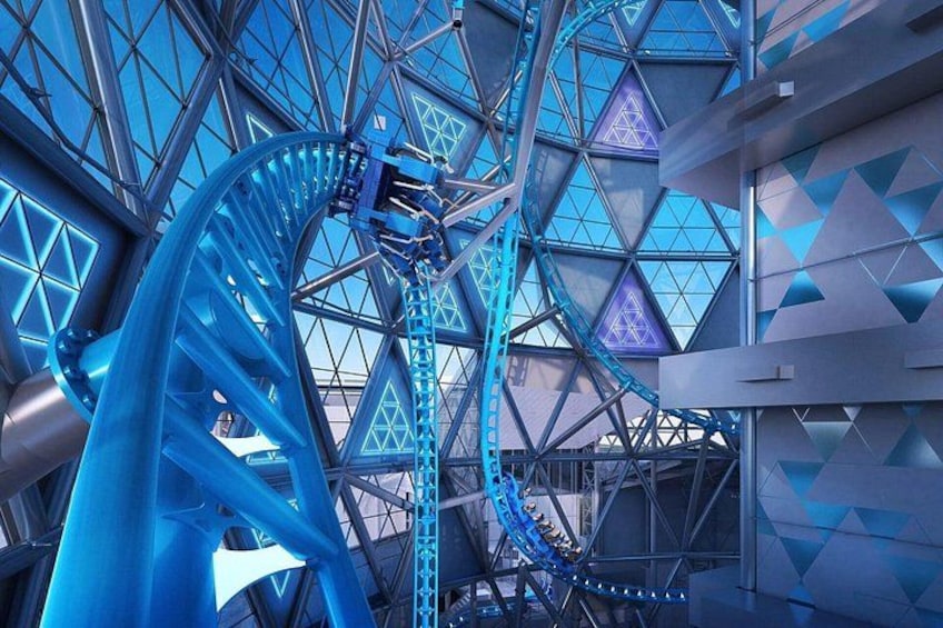 Una montaña rusa con rieles azules y una estructura metálica geométrica al fondo. 5