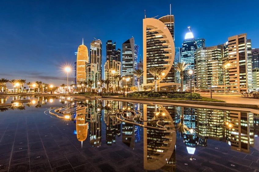 Un horizonte urbano nocturno con edificios iluminados que se reflejan en el agua. 4