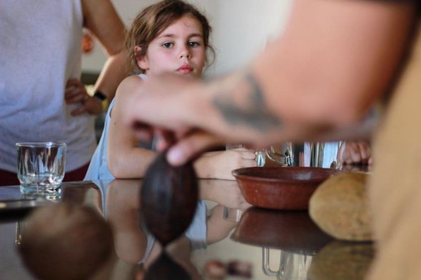 A person holding a ladle over a bowl, with a glass and a spoon on the table. 2