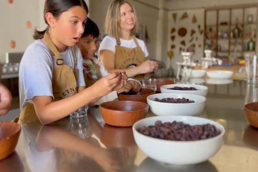 A group of people wearing aprons, engaged in a cooking activity with bowls of ingredients on a table. 1