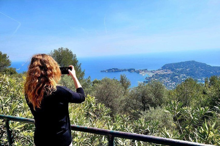 Una persona fotografiando un paisaje costero con árboles y vista al mar. 4