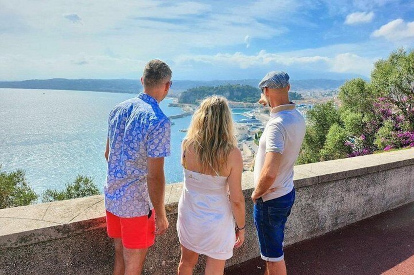 Tres personas sobre un muro de piedra mirando un cuerpo de agua y un paisaje lejano. 3