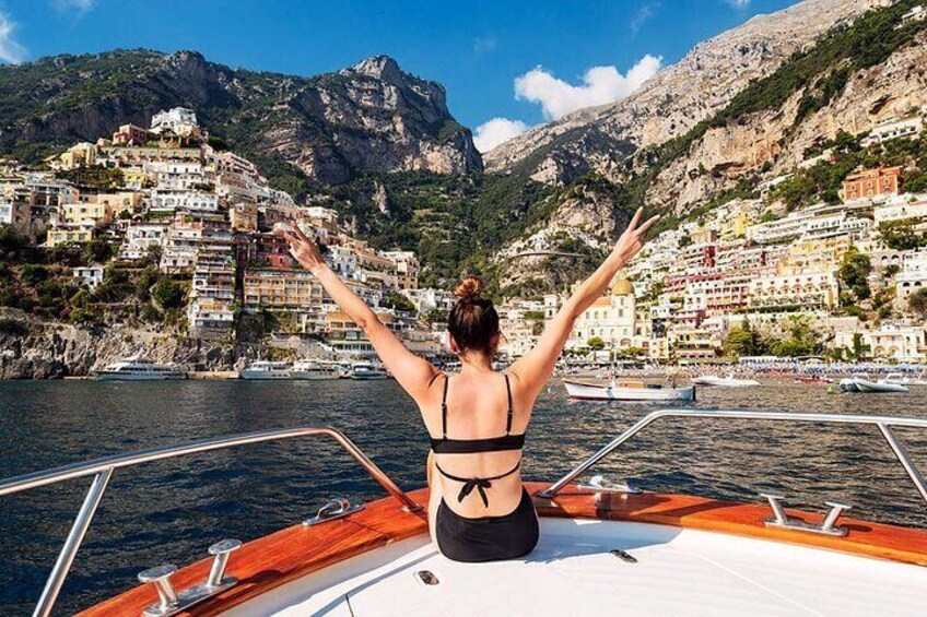 A woman on a boat with mountains and colorful buildings in the background. 2