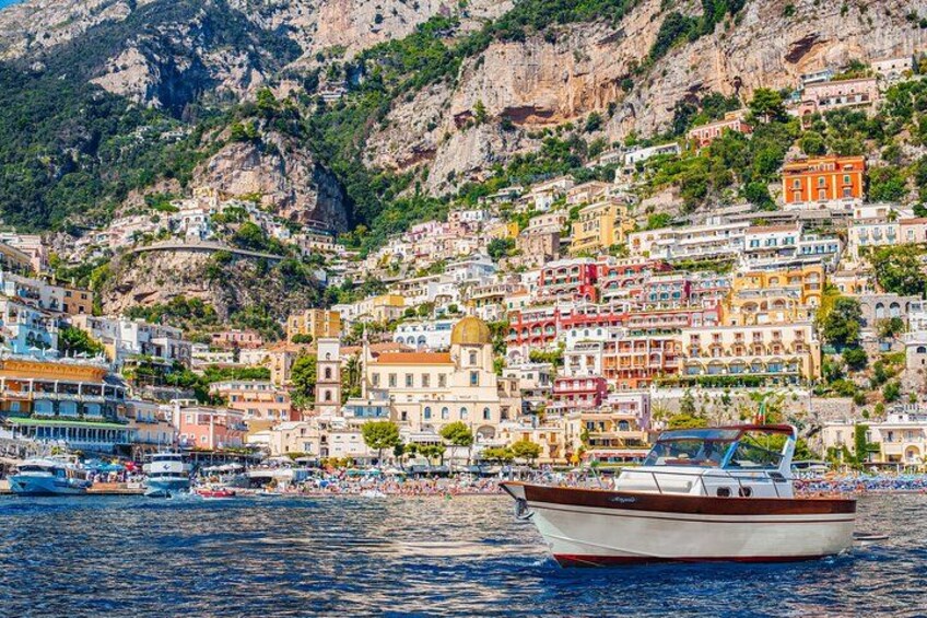 A coastal town with colorful buildings, a boat on the water, and a mountainous backdrop. 3