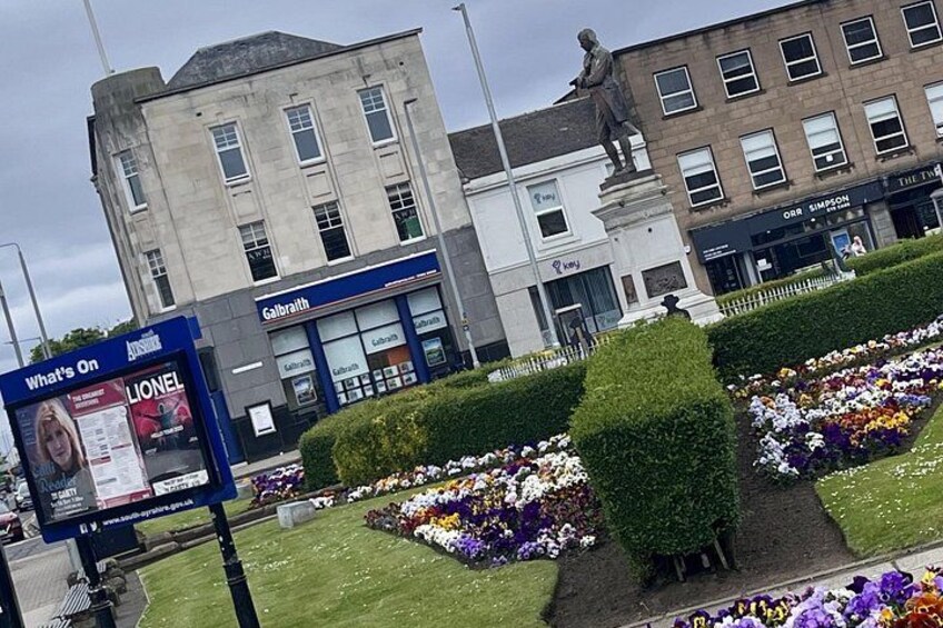 A city square with a statue, flower beds, and buildings including a store named 'Galbraith'. 5