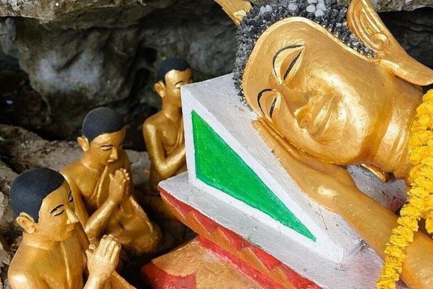A golden statue of a reclining Buddha with a green and white base, surrounded by smaller golden statues of monks. 5